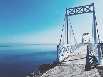 Pier over sea against blue sky