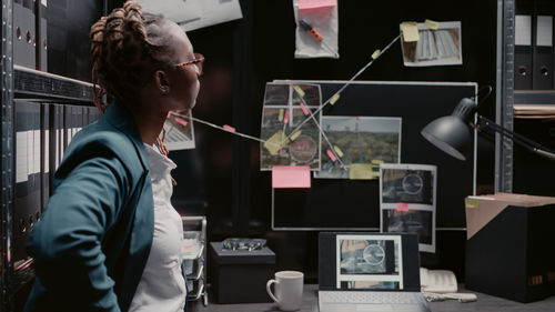 Rear view of man using digital tablet while standing in office