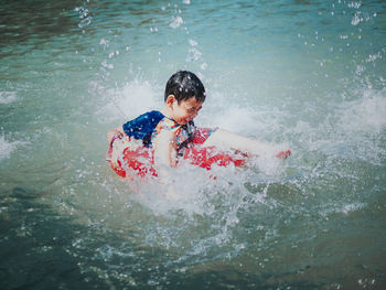 High angle view of boy sitting on inflatable ring at lake