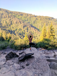 Full length of woman sitting on rock against sky