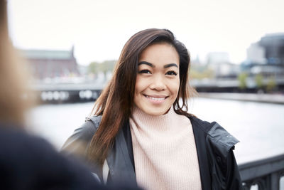 Portrait of smiling woman standing on bridge in city