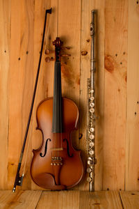 Close-up of violin and flute against wooden wall