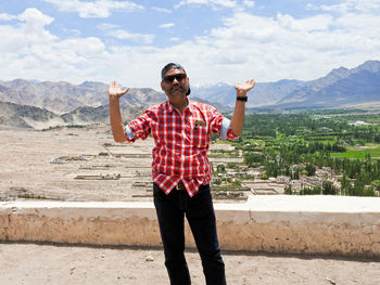 Full length portrait of mature man standing on mountain