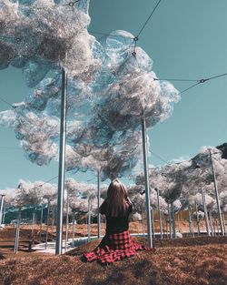 Rear view of woman standing by tree against sky