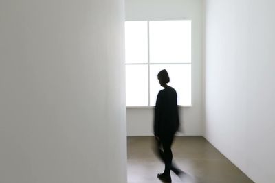 Blurred motion of woman walking in hallway with white wall