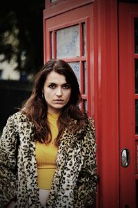 Portrait of beautiful woman standing against red wall