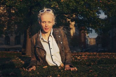 Portrait of young woman standing by tree during autumn