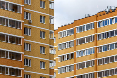 New high rise yellow-orange brick apartment buildings at cloudy day light, close-up telephoto view