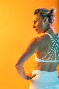 Side view of young woman against yellow background