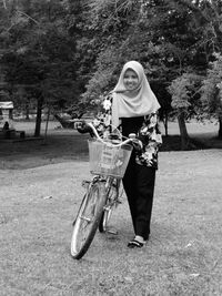 Woman in hijab with bicycle on field