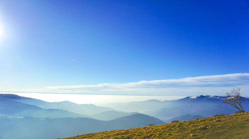 Scenic view of field and mountains against blue sky