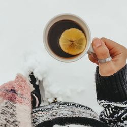 Midsection of woman holding cup of tea with lemon