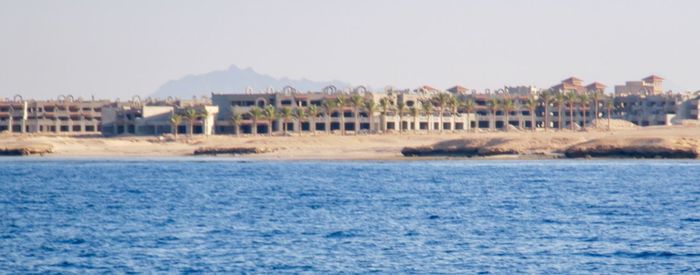 Sea by buildings against sky in city