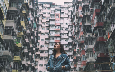 Smiling woman looking up against building in city