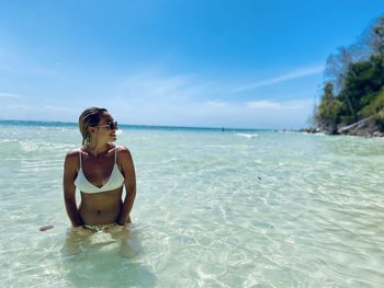 Young woman standing in sea against sky