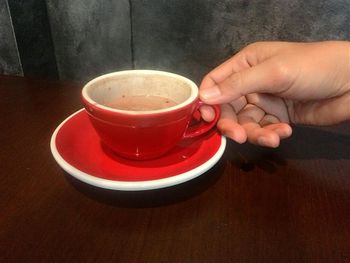 Close-up of hand holding coffee cup on table