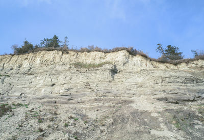 Low angle view of rocks against clear blue sky