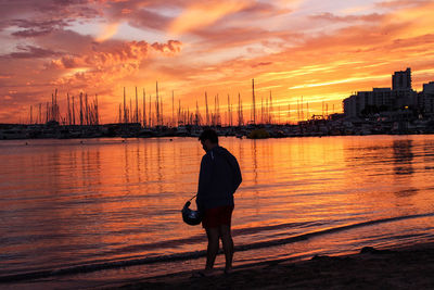 Rear view of woman standing in city against sky during sunset