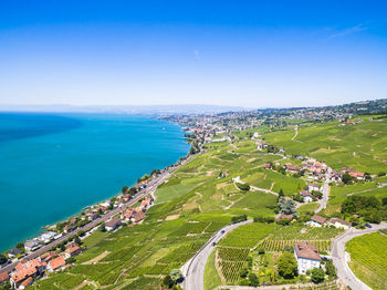 High angle view of city by sea against blue sky