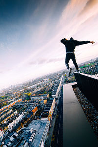 Full length of man jumping in city against sky