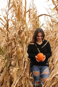 Young woman standing by pumpkins during autumn