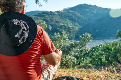 Tourist man resting in olive grove, meditating in front of mountain view or exercising outdoors. 