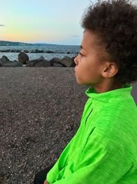 Close-up of boy standing at beach against sky