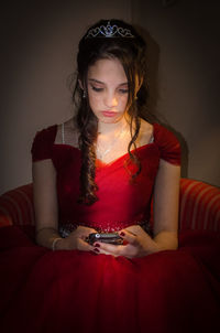 Young woman using mobile phone while sitting in bathroom