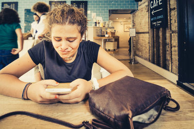 Young woman puckering while using smart phone at cafe