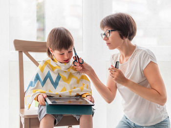 Side view of young woman using mobile phone while sitting at home