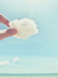 Midsection of person holding ice cream against sky