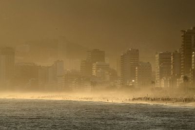 Sea by cityscape against sky