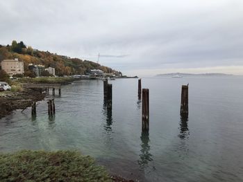 Wooden posts in sea against sky