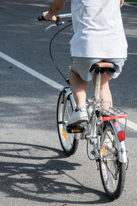 Low section of woman riding bicycle on road