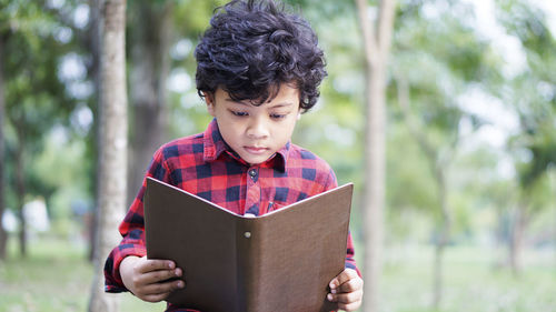 Cute boy reading book in park