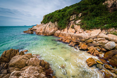 Scenic view of rocks by sea against sky