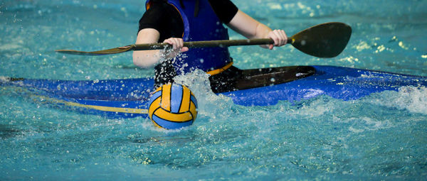 Midsection of man kayaking on swimming pool