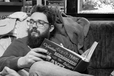 Man with book sitting on sofa at home