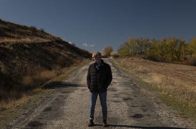 Portrait of adult man in winter cloth on a country road against blue sky. shot in castilla y leon.