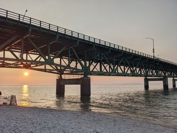 Bridge over river against sky during sunset