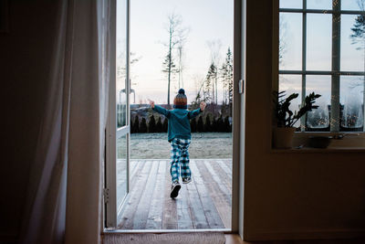 Young boy running out the backdoor to play outside in winter