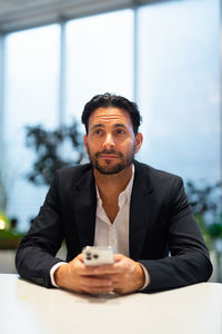 Young man using mobile phone while sitting on table