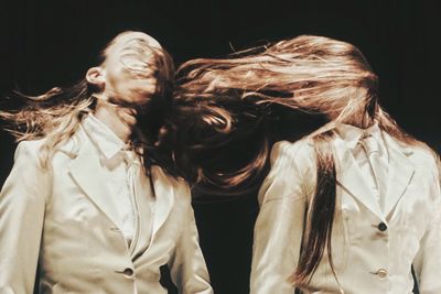 Multiple image of woman tossing hair against black background