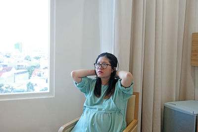 Portrait of young woman sitting on bed at home