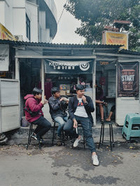 People sitting on chair by street in city