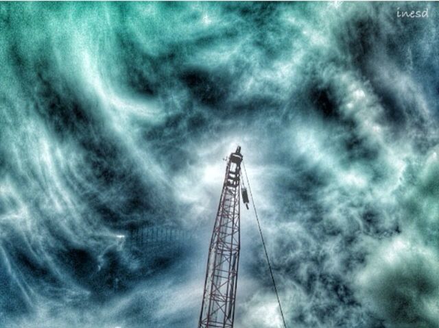 low angle view, sky, cloud - sky, cloudy, cloud, tall - high, overcast, built structure, weather, amusement park, metal, dusk, architecture, outdoors, connection, tower, day, arts culture and entertainment, ferris wheel, no people