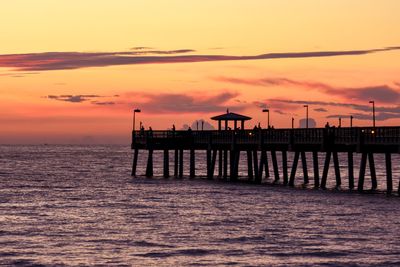 Silhouette pier over sea against sky during sunset