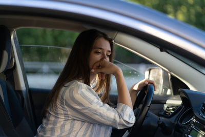 Drunk girl driving car. unhappy tired young female in vehicle suffering from headache or handover