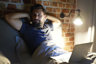 Businessman sleeping with laptop in bedroom