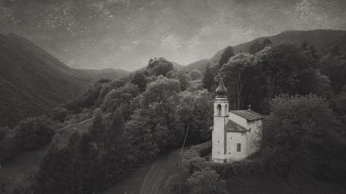 Road amidst trees and buildings against mountain